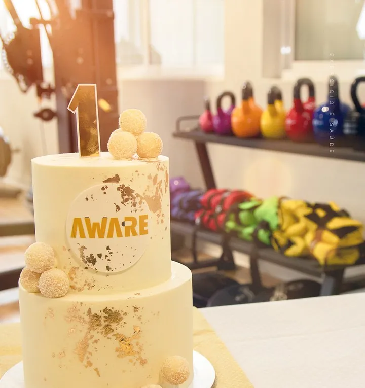 Bolo do primeiro aniversário do AWARE, com os kettlebells ao fundo