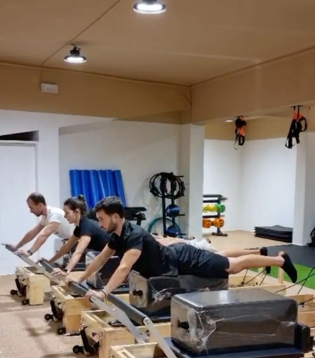 Aula de Pilates Reformer no AWARE, com três alunos nos aparelhos